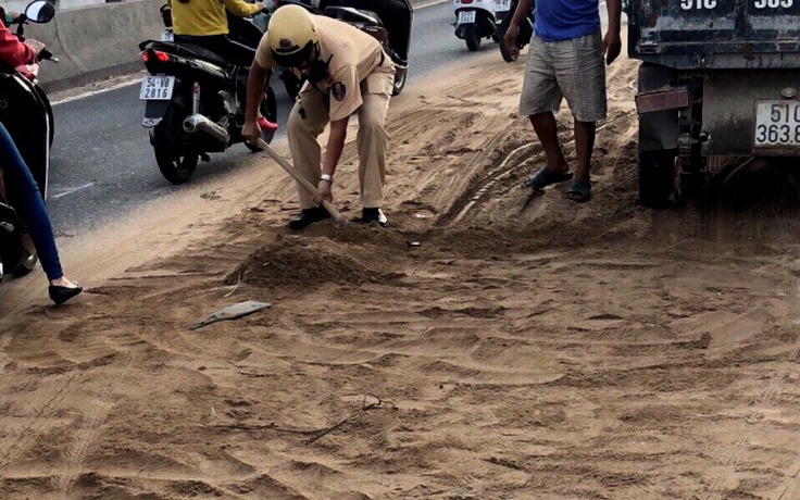 CSGT cùng người dân dọn cát rơi trên đường