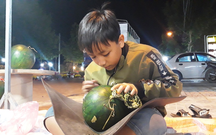 'Nghệ sĩ nhí' khắc chữ thư pháp lên dưa hấu bên chợ hoa tết Kon Tum