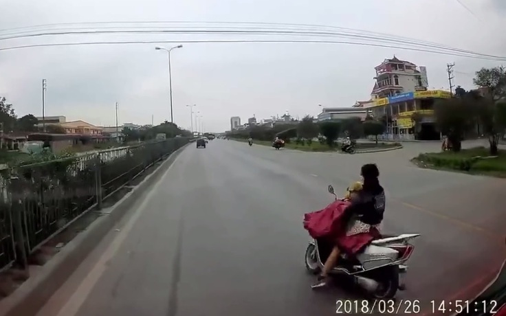 Vừa đi xe máy vừa cởi áo mưa, hai mẹ con may mắn thoát hiểm